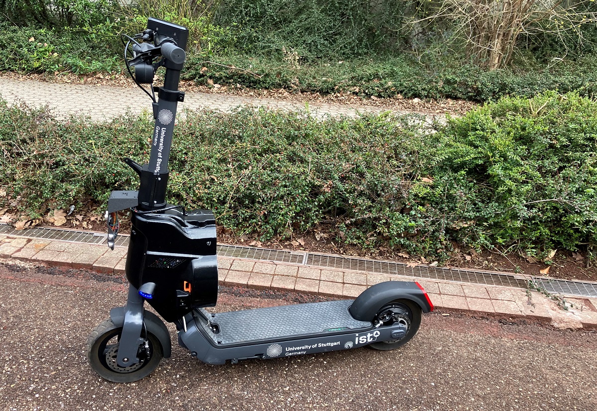 An e-scooter is standing on an asphalt surface.